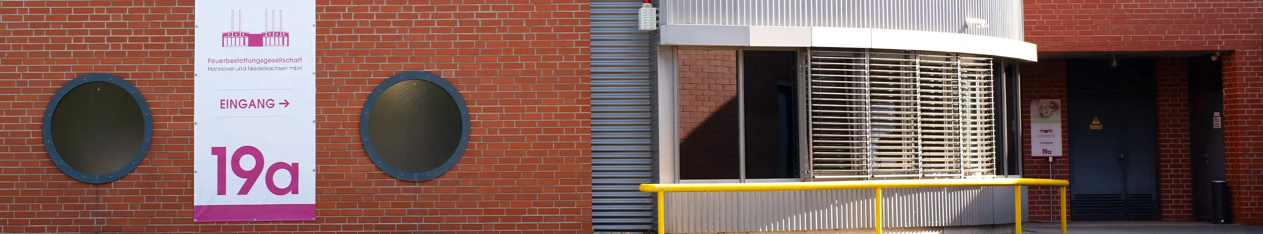 Eingangsbereich der Feuerbestattungsgesellschaft mit Schild und Hausnummer 19a.